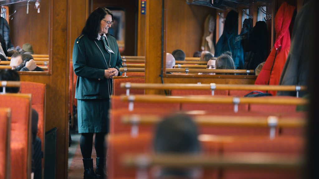 NO: Ulltekstil i gul og rød fargepalett på togseter i moderne toginteriør EN: Wool fabric in grey and warm green tones on seats in a modern train interior
