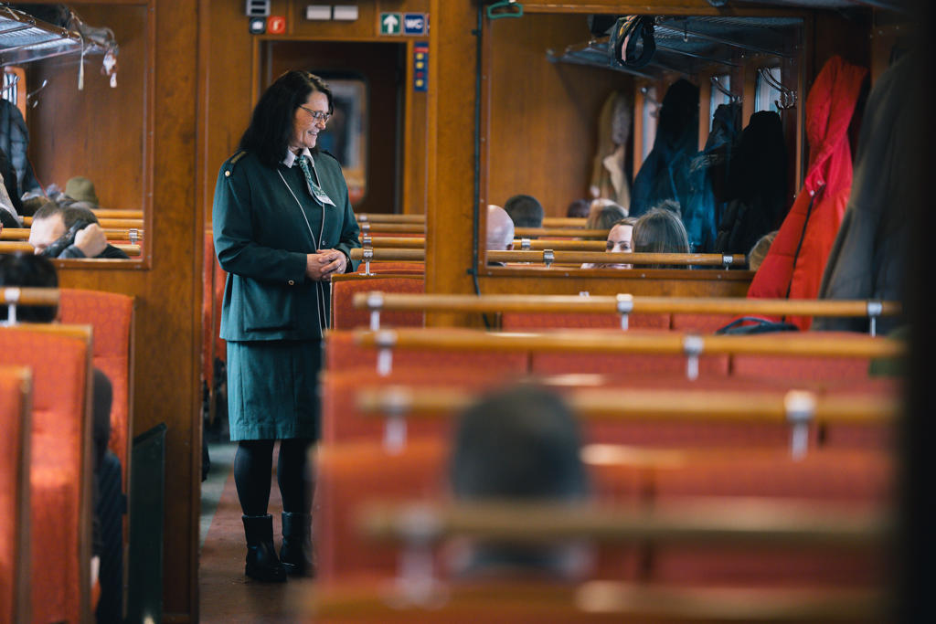 NO: Ulltekstil i gul og rød fargepalett på togseter i moderne toginteriør EN: Wool fabric in grey and warm green tones on seats in a modern train interior